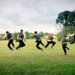 Groom and groomsmen jump high in green grass during wedding ceremony in Nashville Tennessee