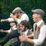 Groom and groomsmen jump in green field at wedding ceremony in Nashville Tennessee