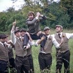 Groomsmen hoist groom up in grassy field at wedding ceremony in Nashville Tennessee