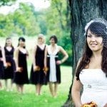 Bride stands in front of tree with bridesmaids in back ground at wedding in Nashville Tennessee