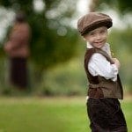 Boy in vest and hat smiles in yard at wedding ceremony in Nashville Tennessee