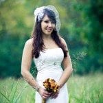 Attractive bride stands with flowers in green field at wedding ceremony in Nashville Tennessee