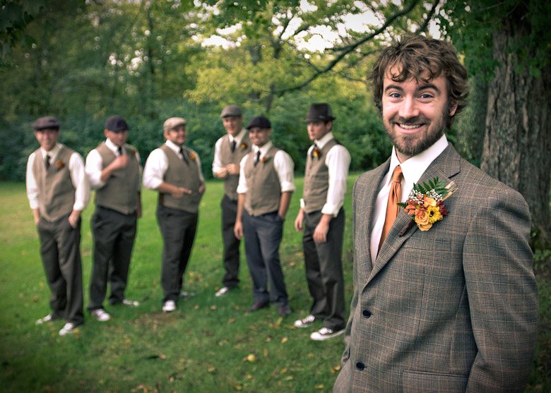 Groom smiles with groomsmen in green grass during wedding ceremony in Nashville Tennessee