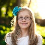 girl with blue bow in hair smiles in sunny yard in Tennessee