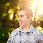 boy smiles and looks over in sunny yard in Tennessee