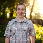 boy in gray shirt smiles in sunny yard in Tennessee
