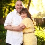husband and wife smile and hug outside in sunny yard in Tennessee