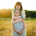 smiling mother and daughter hug outside in sunny field in Tennessee