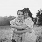 Son and mother smile and hug outside in sunny field in Tennessee