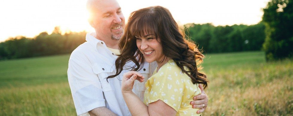 woman and man smile and embrace in sunny field in Tennessee