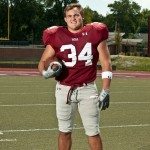 young football player stands on filed holding football in Tennessee