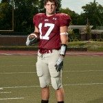 Football player stands on field holding football in Tennessee