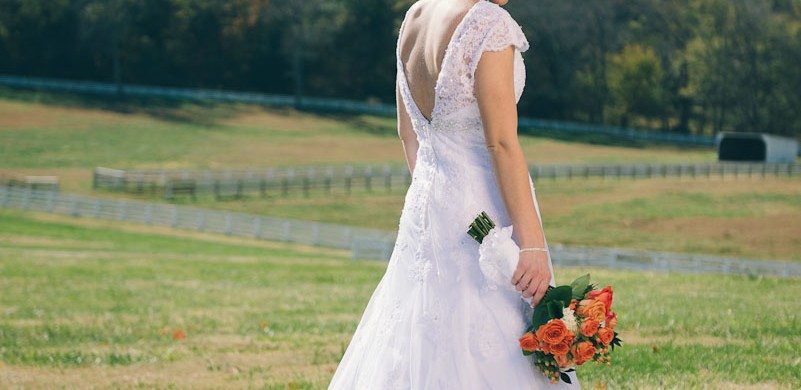 Bride looks at grass as she stands in sunny field before wedding in Tennessee