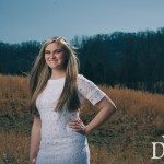 Smiling young blonde girl in white dress standing in field in Tennessee