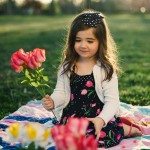 Daughter sits on blanket outside and holds flowers in Tennessee