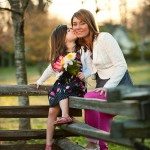daughter kisses mother on check outside on old fence in Tennessee