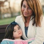Mother and daughter sit covered with blanket outside on bench in Tennessee