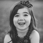 child smiles and sits in grass outside in Tennessee