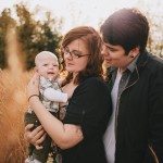 Couple holds baby in grass field for family portrait in Nashville Tennessee