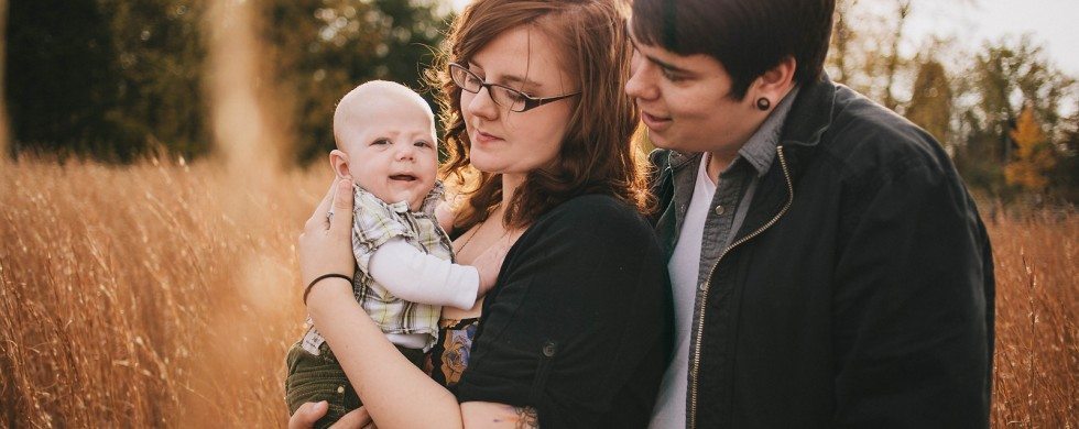 Couple holds baby in grass field for family portrait in Nashville Tennessee