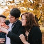 Couple holds baby in Autumn landscape for portrait in Nashville Tennessee