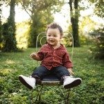 Smiling child sits in chair in green grass for family portrait in Nashville Tennessee