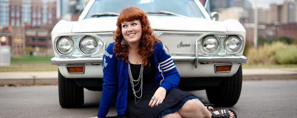 Red headed girl sits in front of white Corvair in Nashville Tennessee