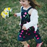 smiling child runs with flowers in yard in Tennessee