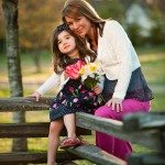 Mother and daughter smile and sit on old fence in Tennessee