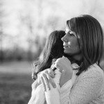 Mother holds daughter and looks on outside in field in Tennessee